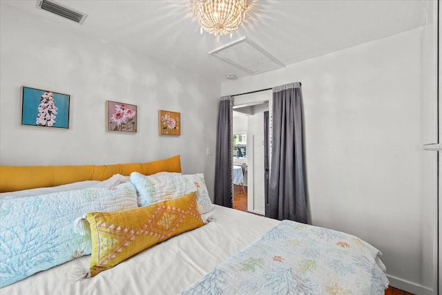 bedroom with attic access, wood finished floors, and visible vents