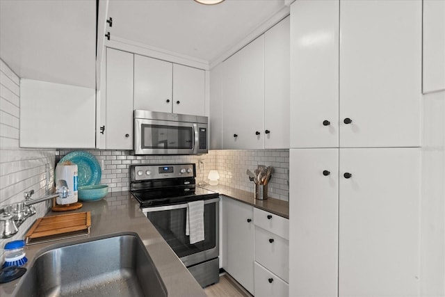 kitchen with backsplash, white cabinets, appliances with stainless steel finishes, and a sink