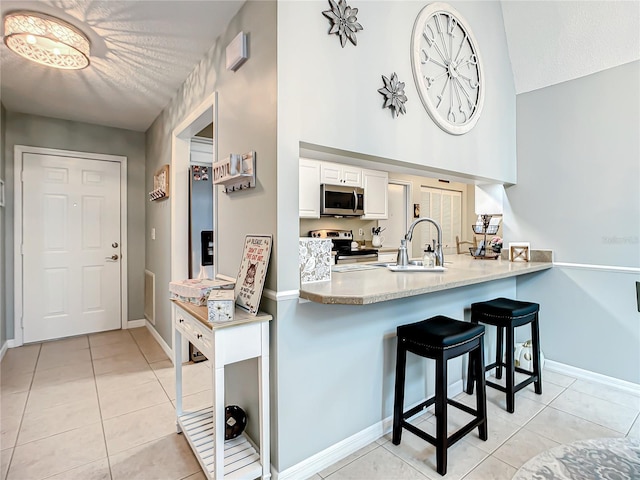kitchen with baseboards, stainless steel appliances, light tile patterned flooring, and a sink