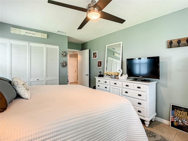 tiled bedroom with a ceiling fan, baseboards, visible vents, and a closet