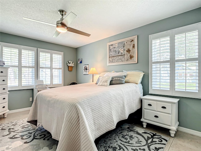 bedroom featuring baseboards, a ceiling fan, and a textured ceiling