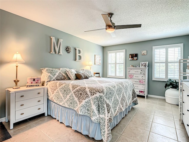 bedroom with light tile patterned flooring, a textured ceiling, a ceiling fan, and baseboards