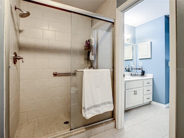 bathroom featuring a textured ceiling, tile patterned floors, a shower stall, and vanity