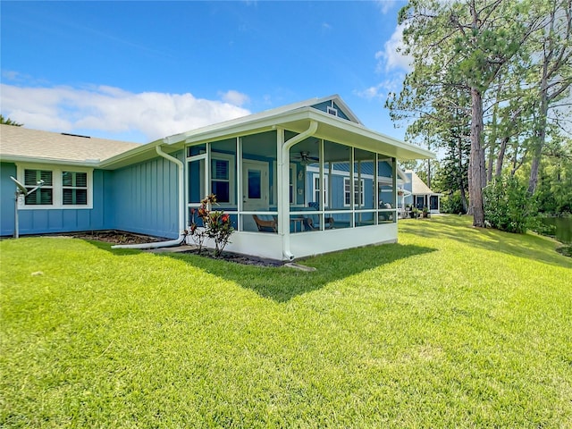 back of property featuring board and batten siding, a lawn, ceiling fan, and a sunroom