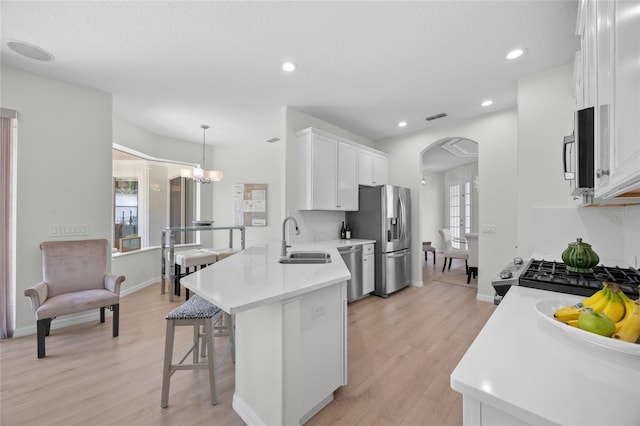 11222 Rapallo Ln, Windermere, FL 34786 - kitchen featuring stainless steel appliances, arched walkways, white cabinetry, a sink, and a breakfast bar