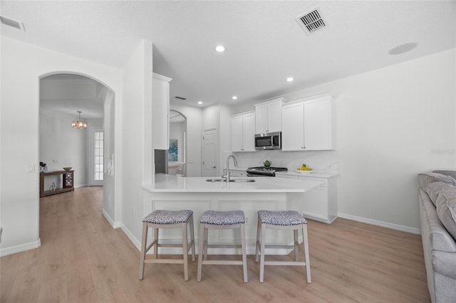 11222 Rapallo Ln, Windermere, FL 34786 - kitchen with stainless steel appliances, a sink, a kitchen breakfast bar, white cabinetry, and light wood finished floors