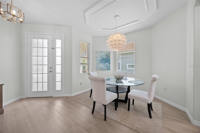 11222 Rapallo Ln, Windermere, FL 34786 - dining room featuring a chandelier, light wood-type flooring, a raised ceiling, and baseboards