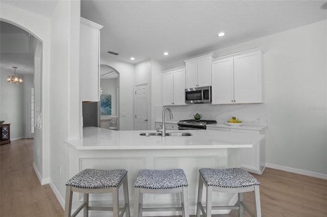 11222 Rapallo Ln, Windermere, FL 34786 - kitchen with appliances with stainless steel finishes, a sink, light wood finished floors, arched walkways, and recessed lighting