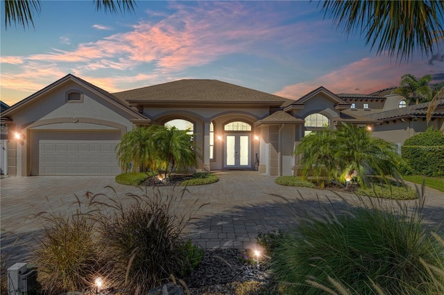 mediterranean / spanish home with french doors, stucco siding, and decorative driveway