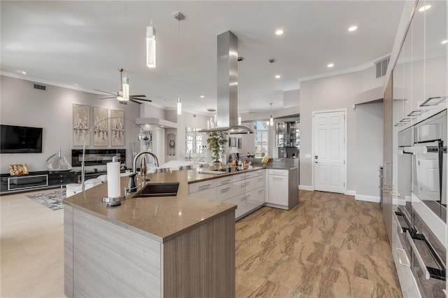 kitchen with visible vents, crown molding, island range hood, a sink, and open floor plan