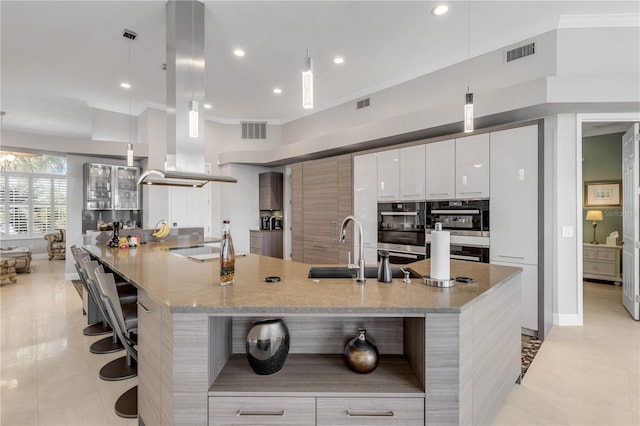 kitchen with a sink, modern cabinets, visible vents, and a kitchen bar