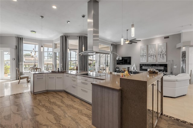 kitchen featuring a ceiling fan, decorative light fixtures, open floor plan, island exhaust hood, and ornamental molding