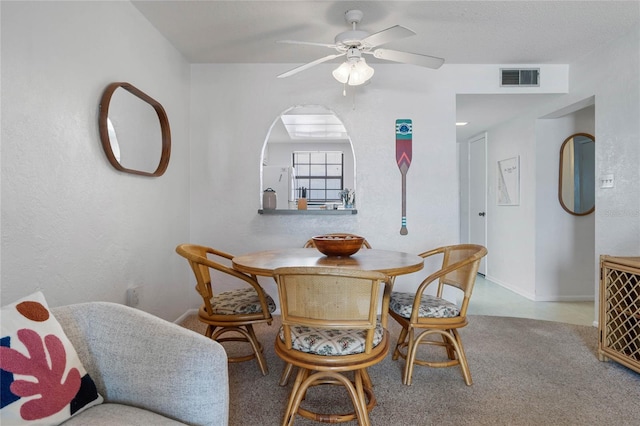 dining space with arched walkways, ceiling fan, visible vents, and baseboards