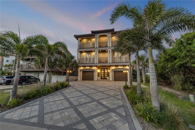 6771 Turtlemound Rd, New Smyrna Beach, FL 32169 - coastal inspired home with a balcony, driveway, stucco siding, and an attached garage