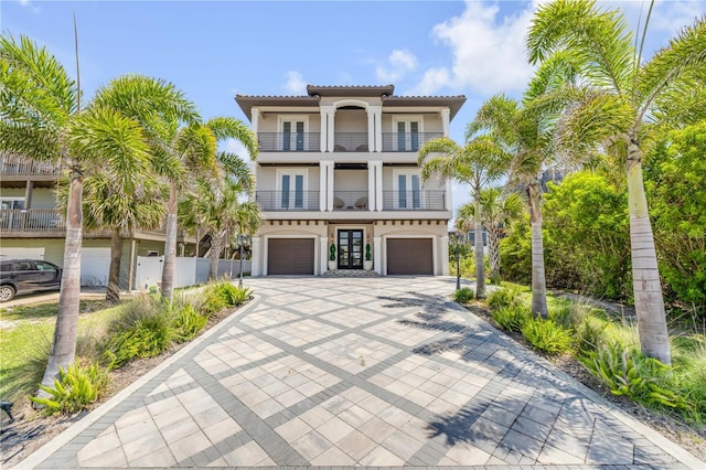 6771 Turtlemound Rd, New Smyrna Beach, FL 32169 - raised beach house with an attached garage, french doors, driveway, a balcony, and stucco siding