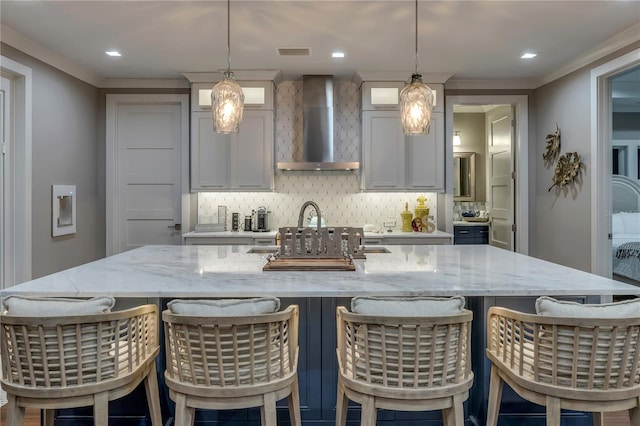 6771 Turtlemound Rd, New Smyrna Beach, FL 32169 - kitchen with wall chimney range hood, a large island, light stone counters, backsplash, and hanging light fixtures