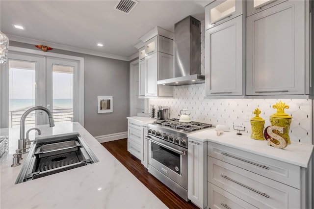 6771 Turtlemound Rd, New Smyrna Beach, FL 32169 - kitchen featuring a sink, visible vents, wall chimney exhaust hood, decorative backsplash, and stainless steel stove