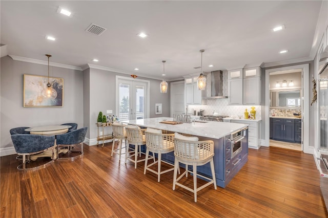 6771 Turtlemound Rd, New Smyrna Beach, FL 32169 - kitchen featuring light stone countertops, visible vents, a large island, wall chimney range hood, and tasteful backsplash