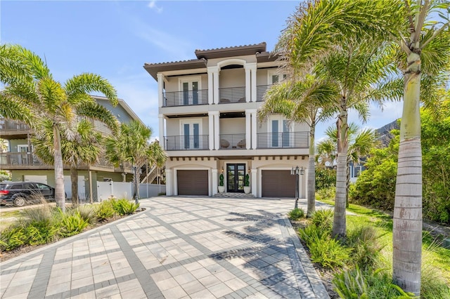 6771 Turtlemound Rd, New Smyrna Beach, FL 32169 - view of front facade with french doors, a garage, stucco siding, a balcony, and driveway