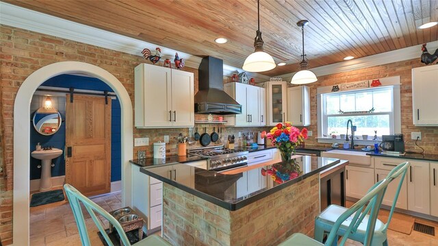 508 Faulkner St, New Smyrna Beach, FL 32168 - kitchen with wall chimney range hood, a barn door, dark countertops, wood ceiling, and range with gas stovetop