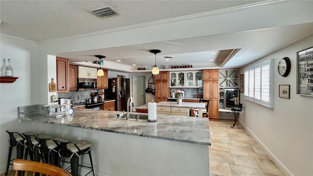 34 Richmond Dr, New Smyrna Beach, FL 32169 - kitchen featuring visible vents, a sink, a peninsula, decorative backsplash, and stainless steel appliances