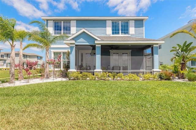 view of front of home featuring roof with shingles, a ceiling fan, a sunroom, and a front lawn