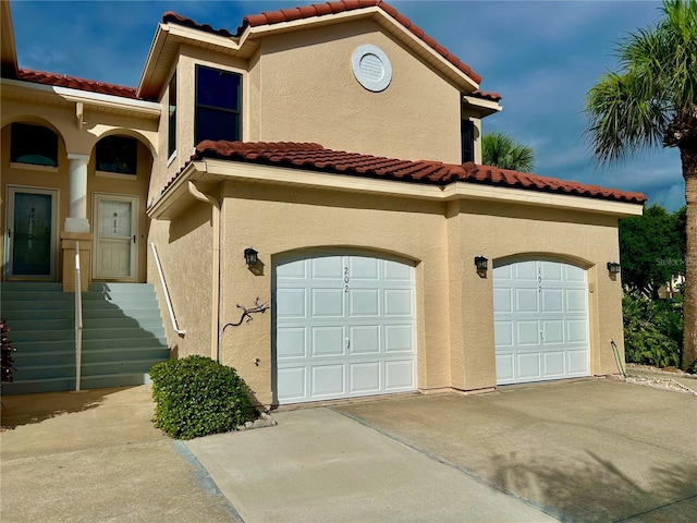 439 Bouchelle Dr Unit 202, New Smyrna Beach, FL 32169 - view of front of house with a garage, stucco siding, a tile roof, and concrete driveway