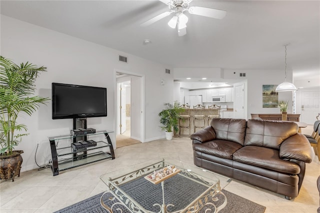 living area with light tile patterned floors and a ceiling fan