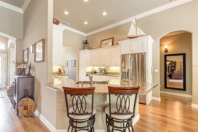 kitchen featuring a peninsula, a kitchen bar, arched walkways, and a sink