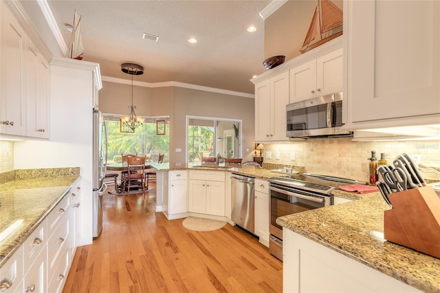 kitchen featuring a peninsula, ornamental molding, white cabinetry, and appliances with stainless steel finishes