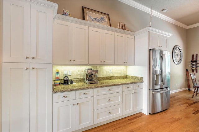 kitchen with light wood-style flooring, stainless steel refrigerator with ice dispenser, white cabinets, crown molding, and backsplash