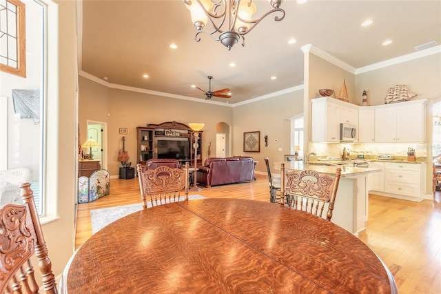 dining room featuring light wood finished floors, visible vents, arched walkways, ornamental molding, and recessed lighting