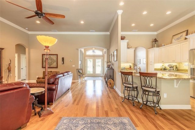 interior space featuring arched walkways, light wood-type flooring, and a ceiling fan