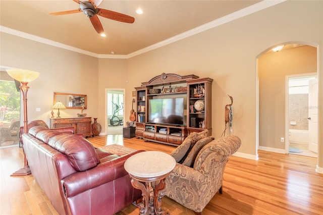 living area with arched walkways, a healthy amount of sunlight, light wood finished floors, and a ceiling fan
