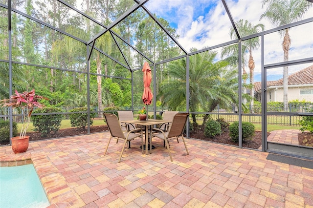 view of patio featuring outdoor dining area, fence, and a lanai
