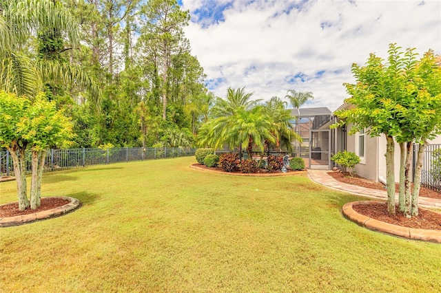 view of yard featuring fence and glass enclosure