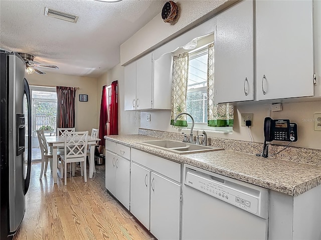 kitchen with visible vents, stainless steel fridge, light countertops, a sink, and dishwasher