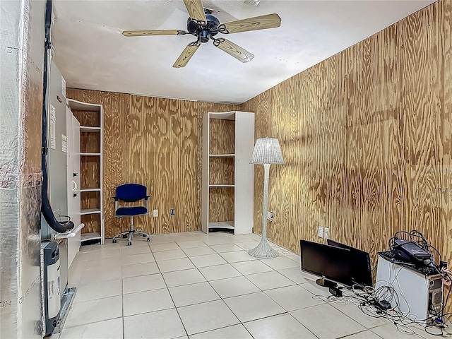 unfurnished office featuring tile patterned flooring, ceiling fan, and wooden walls