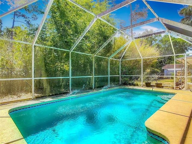 outdoor pool featuring glass enclosure and a patio