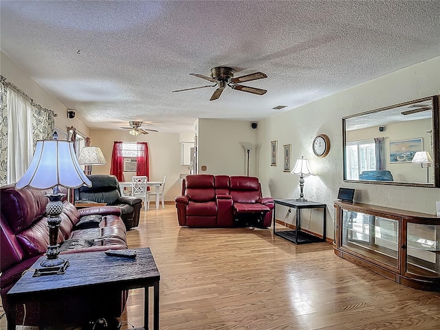living area with visible vents, a ceiling fan, a textured ceiling, and wood finished floors