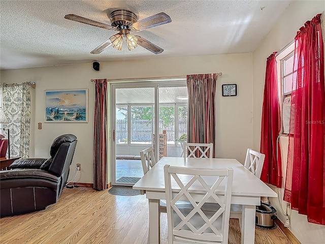 dining room featuring light wood-type flooring, a textured ceiling, ceiling fan, and baseboards
