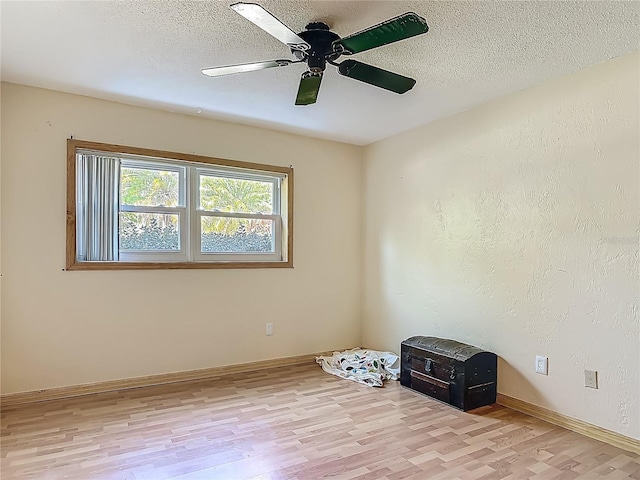 spare room with baseboards, a ceiling fan, light wood-type flooring, and a textured ceiling