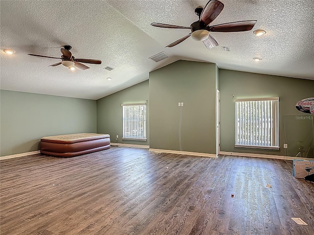 additional living space with ceiling fan, visible vents, wood finished floors, and vaulted ceiling