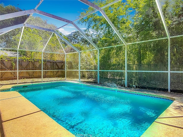 view of swimming pool featuring a fenced backyard, a fenced in pool, and glass enclosure