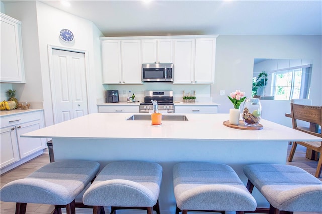 kitchen featuring a sink, light countertops, stainless steel appliances, and a kitchen bar