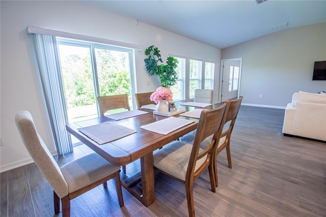 dining area with baseboards, lofted ceiling, wood finished floors, and visible vents