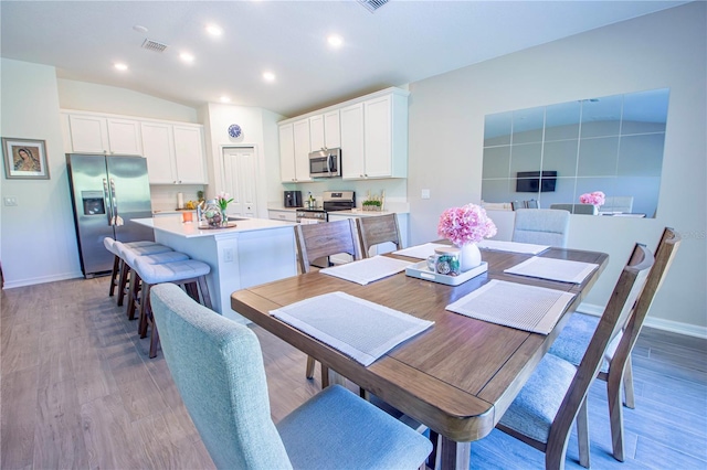 dining space featuring visible vents, light wood-style floors, and baseboards