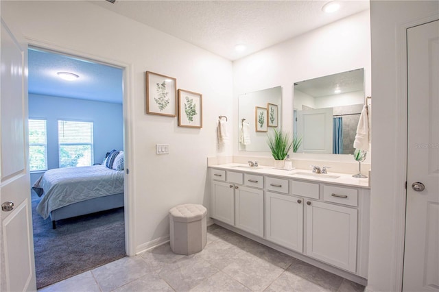 bathroom with double vanity, a sink, a textured ceiling, and ensuite bath