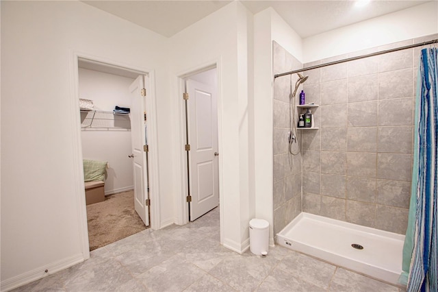 bathroom with baseboards, a stall shower, and a spacious closet