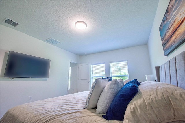 bedroom with a textured ceiling and visible vents